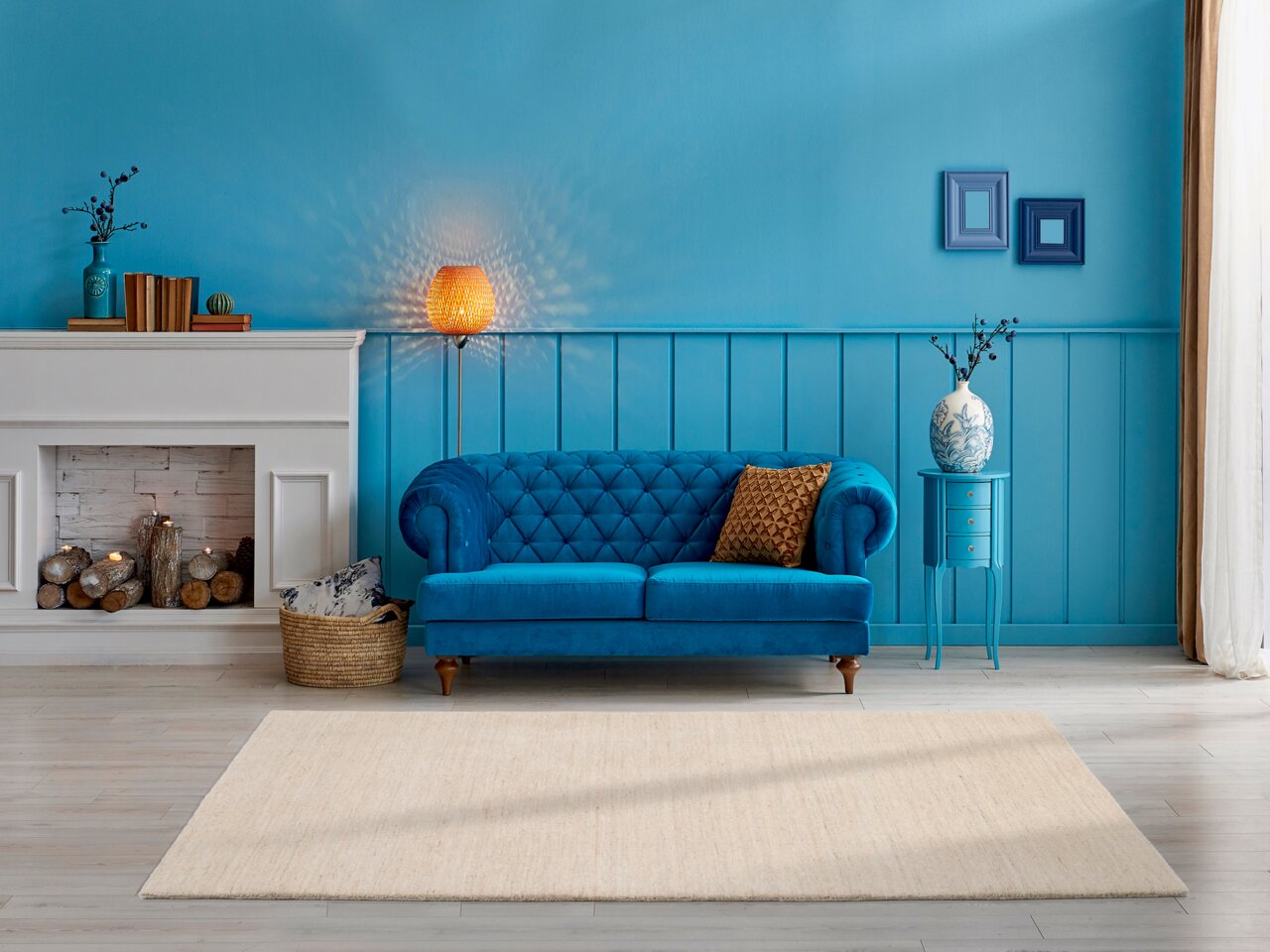Ein heller Wollteppich liegt in einem stilvoll eingerichteten Wohnzimmer mit blauer Wand, einem blauen Sofa und einem Kamin. Die Perspektive zeigt den Teppich von oben in einem gemütlichen Ambiente.