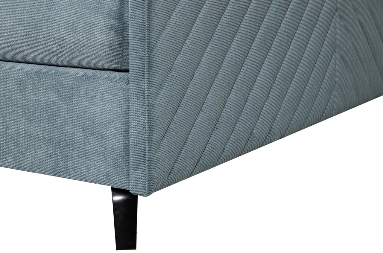 Nahaufnahme eines Boxspringbettes in grauem Stoff mit diagonalen Nähten und schwarzen Metallfüßen, Perspektive von der Ecke.