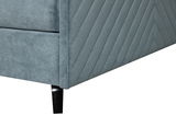 Nahaufnahme eines Boxspringbettes in grauem Stoff mit diagonalen Nähten und schwarzen Metallfüßen, Perspektive von der Ecke.