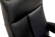 Close-up van een zwarte lederen relaxfauteuil, gezien vanaf de zijkant.