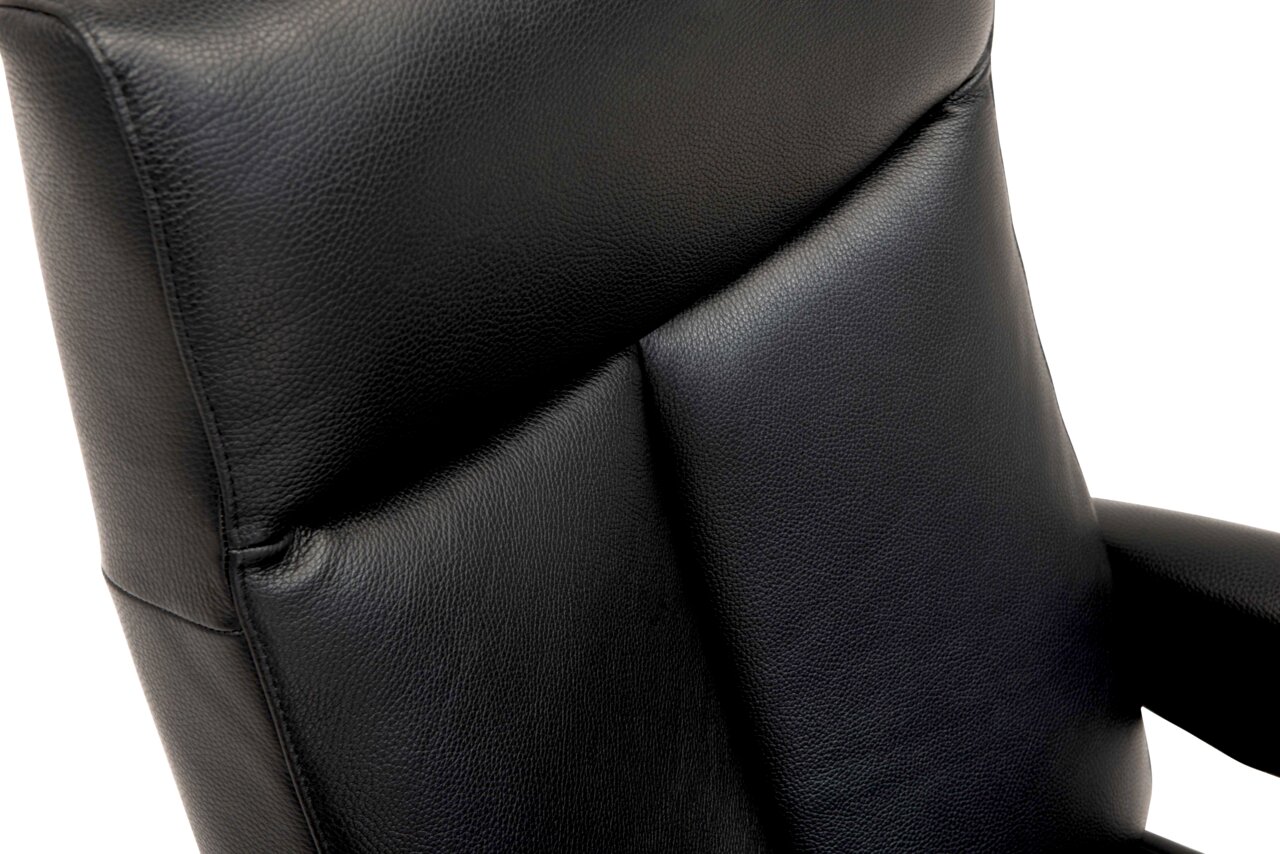 Close-up van een zwarte lederen relaxfauteuil, gezien vanaf de zijkant.