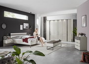 Moderne Schlafzimmeransicht mit Nachtkonsolen, Bett und Schrank in einem stilvollen, hellen Raum.