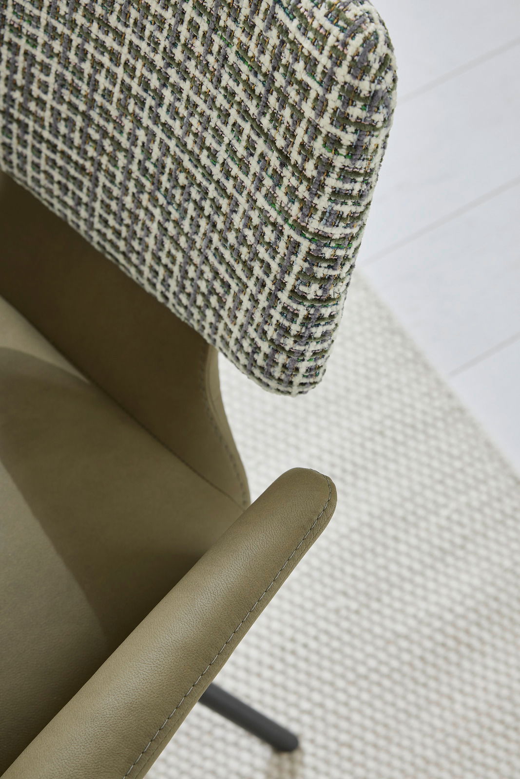 Detailansicht eines Sessels mit grünem Lederbezug und gemustertem Stoffrücken aus der Vogelperspektive.