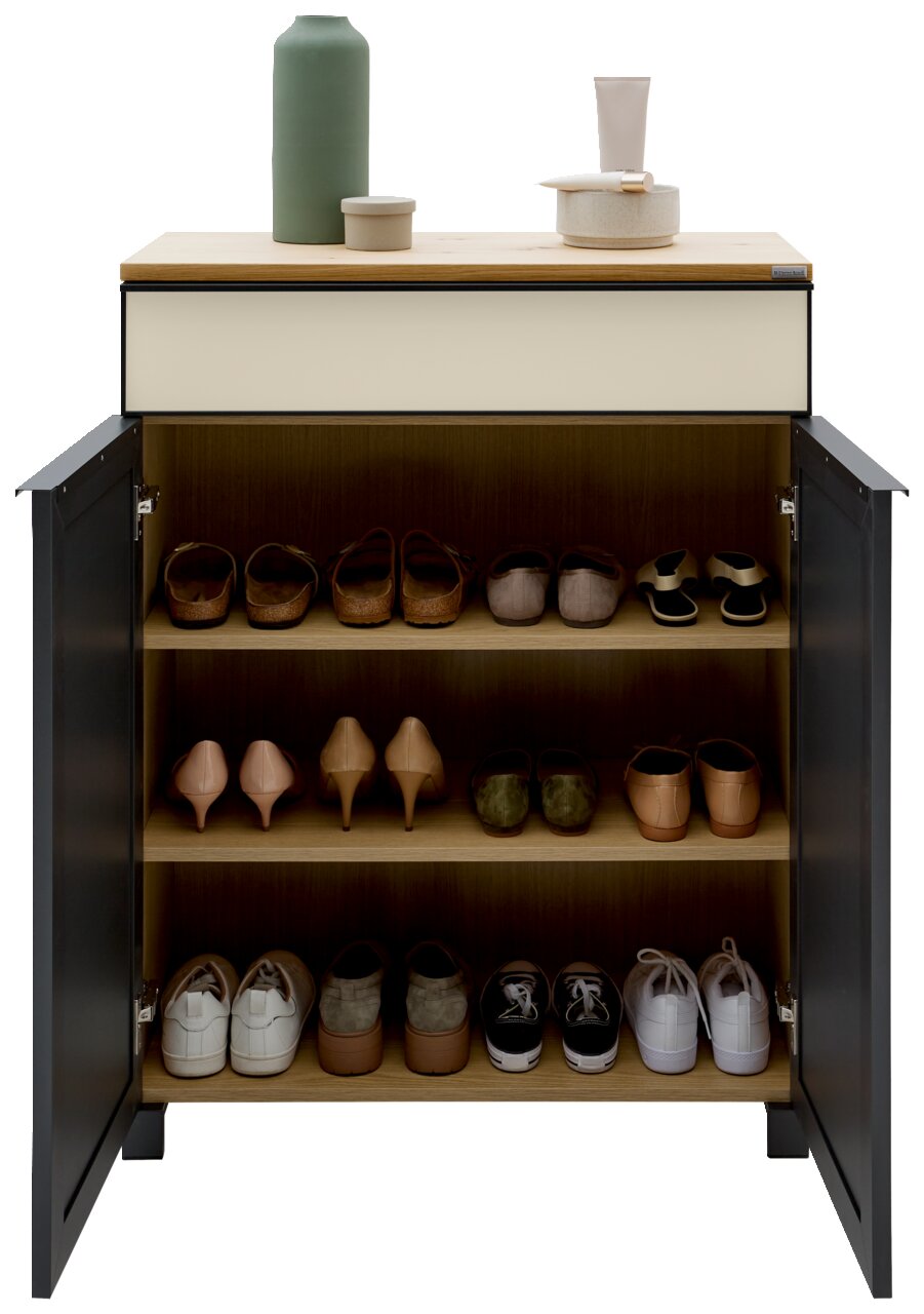 Schuhschrank mit geöffneter Tür, gefüllt mit verschiedenen Schuhen auf drei Regalböden, aus der Frontalperspektive fotografiert. Oben auf dem Schrank stehen dekorative Gegenstände.