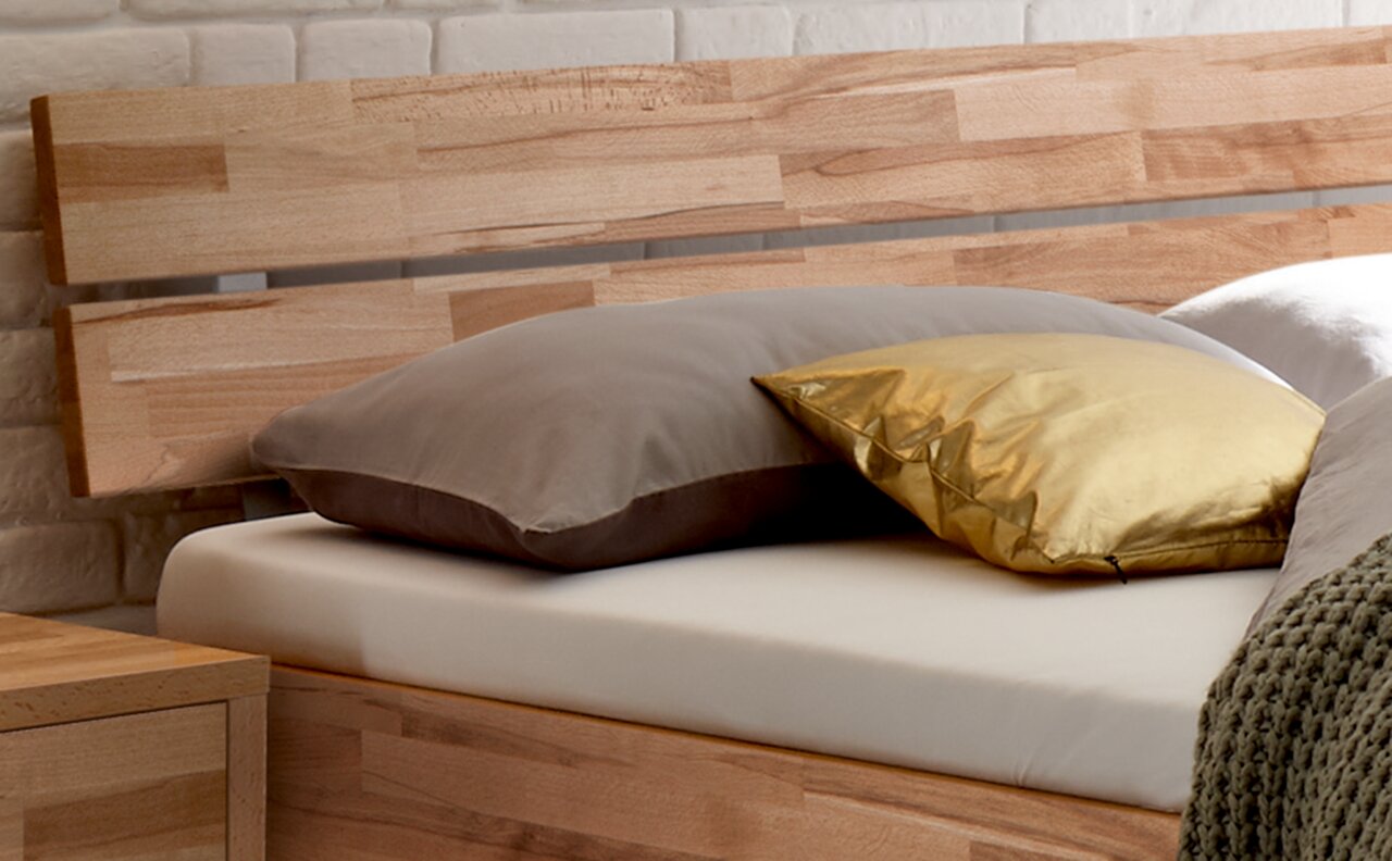 Holz-Kopfteil mit natürlicher Maserung, seitliche Perspektive, dekoriert mit Kissen in Grau und Gold.