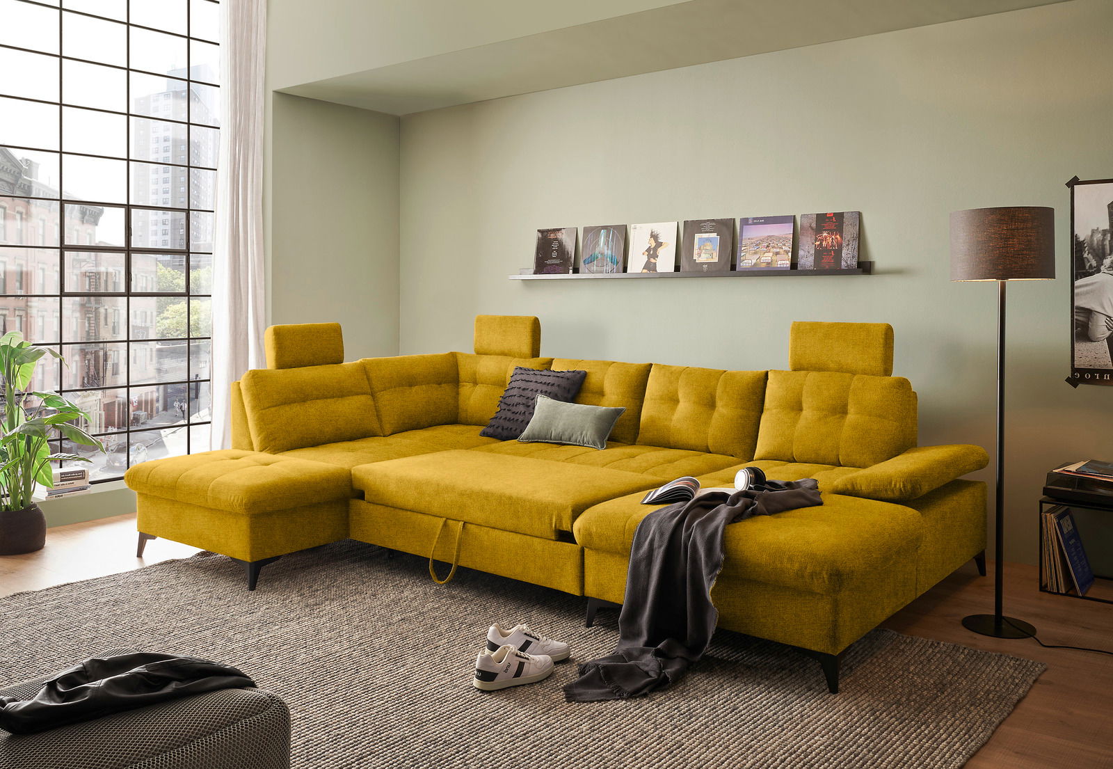 Gelbes Ecksofa in einem modernen Wohnzimmer, mit Blick von schräg vorne. Das Sofa hat verstellbare Kopfstützen und ist mit Kissen dekoriert.