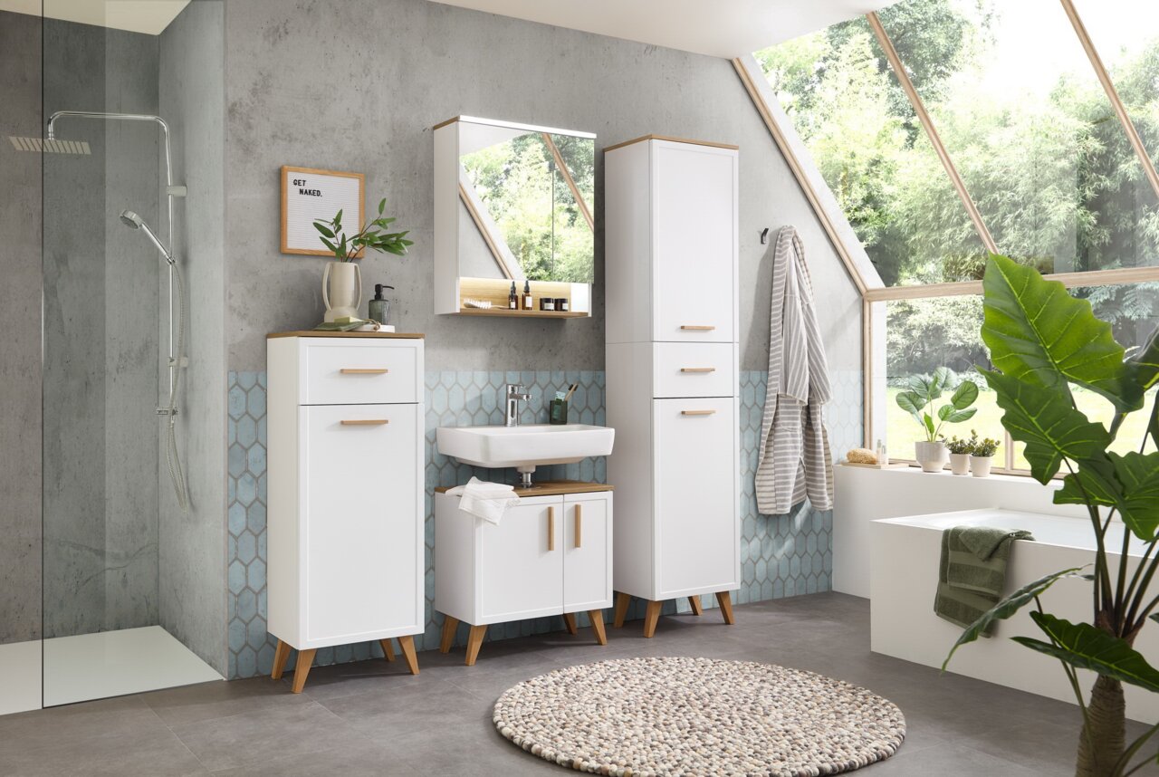 Modernes Badezimmer mit weißem Möbel-Set, bestehend aus einem hohen Schrank, einem Waschbeckenunterschrank und einem Spiegelschrank, auf schräg einfallendes Tageslicht ausgerichtet.
