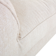 Nahaufnahme eines cremefarbenen Big-Sofas mit weicher Textur, seitliche Perspektive.