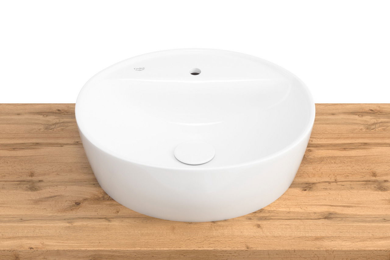 Runder, weißer Waschtisch auf einer Holzoberfläche, aus der Vogelperspektive fotografiert.