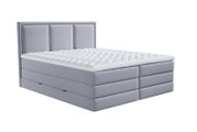 Lichtgrijs gestoffeerd tweepersoons boxspringbed met hoog, driedelig gecapitonneerd hoofdbord en witte doorgestikte topper, schuin van voren afgebeeld