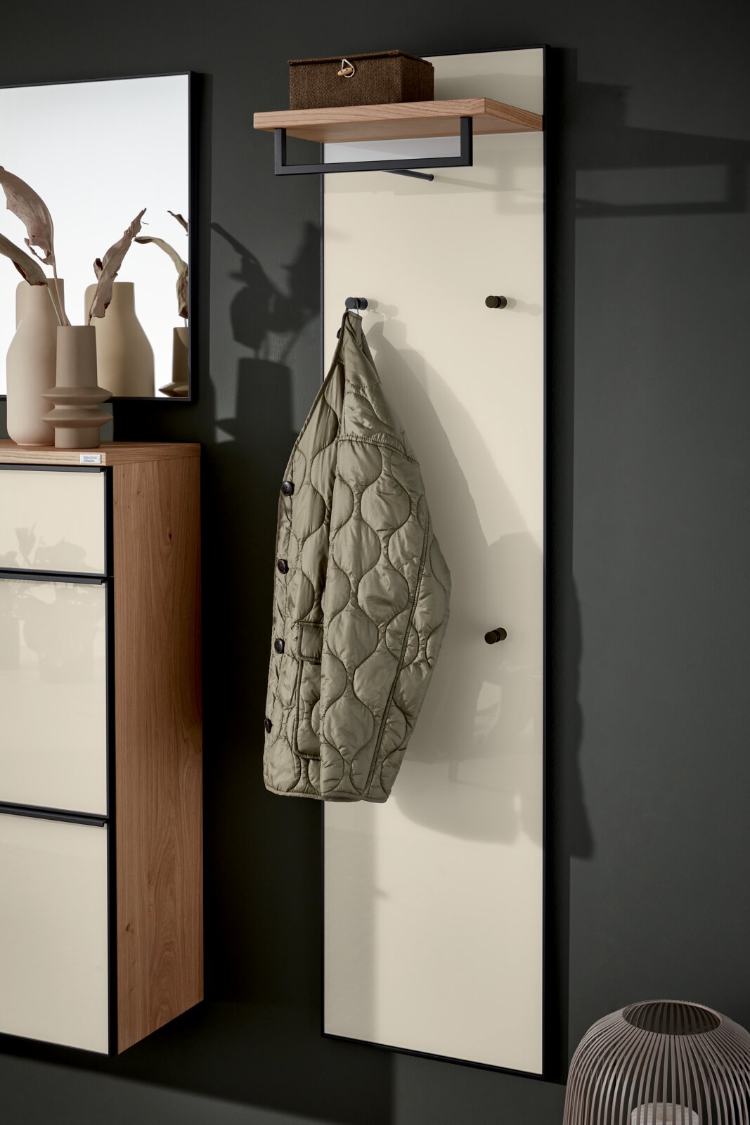 Kastpaneel met een opgehangen jas, een plank bovenaan en een modern, minimalistisch ontwerp. Zijaanzicht.