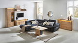 Moderne Wohnzimmeransicht mit einer Vitrine aus Holz, die links im Bild steht. Die Vitrine hat eine Glasfront und ist von einem schwarzen Rahmen umgeben. Sie ist Teil eines stilvollen Wohnzimmersets mit einem großen, dunklen Ecksofa und einem Holzcouchtis