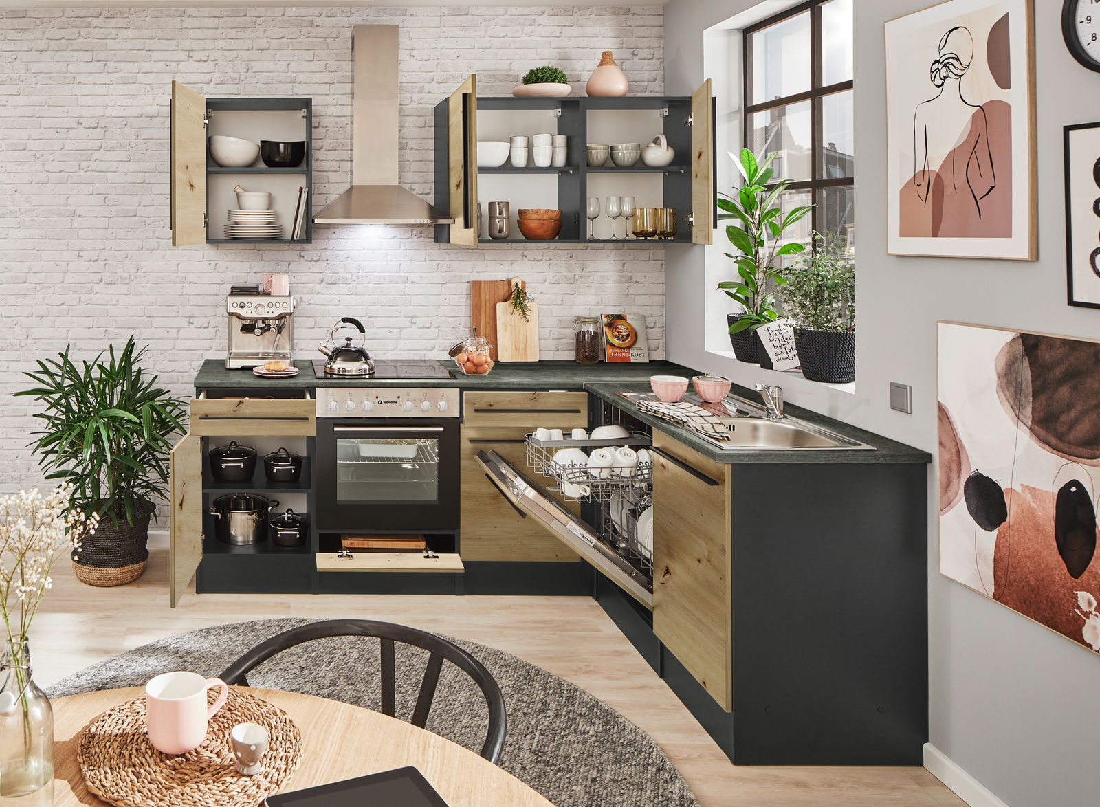 Moderne Küche mit Eckunterschrank, offener Geschirrspüler und Herd, aus der Perspektive eines Esstisches fotografiert.