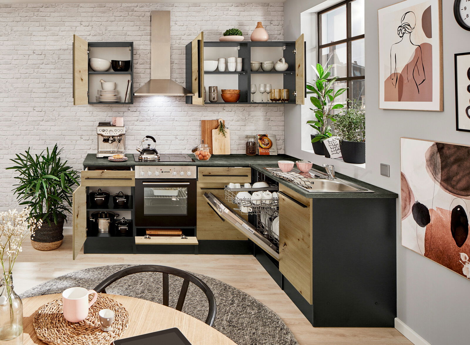 Moderne Küche mit Eckunterschrank, offener Geschirrspüler und Herd, aus der Perspektive eines Esstisches fotografiert.