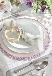 Elegantes Tafelset in Weiß mit dekorativem Herz und Blume, von oben fotografiert.