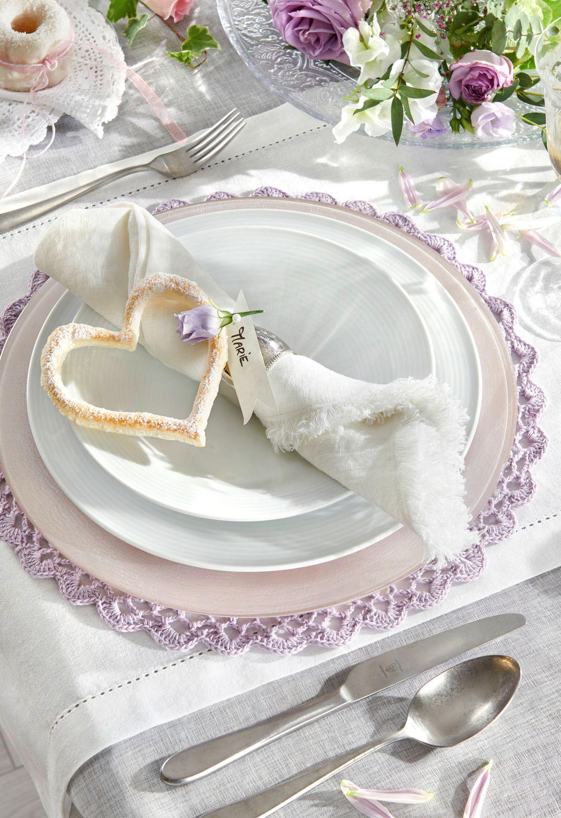 Elegantes Tafelset in Weiß mit dekorativem Herz und Blume, von oben fotografiert.