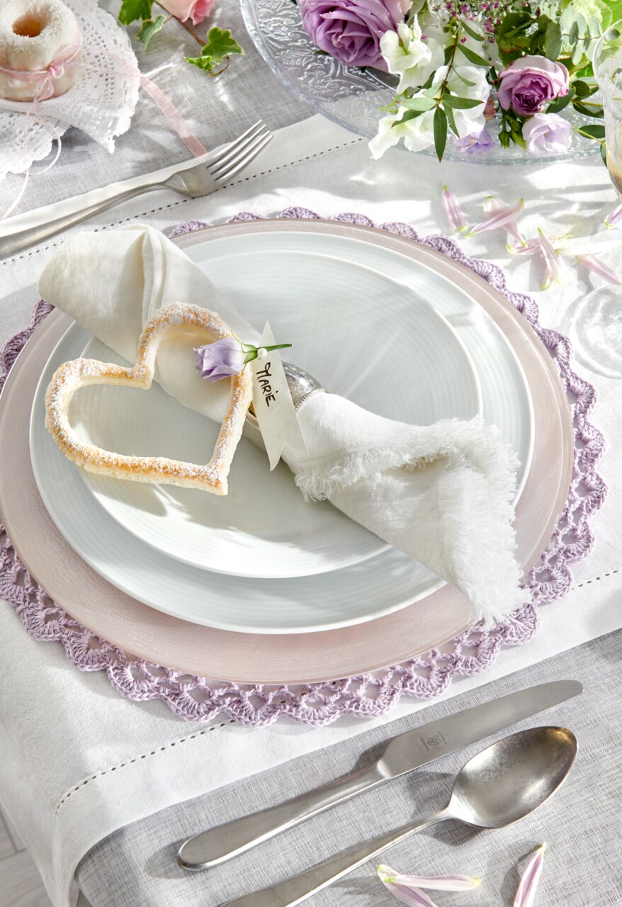 Elegante servieset in wit met decoratief hartje en bloem, gefotografeerd van bovenaf.