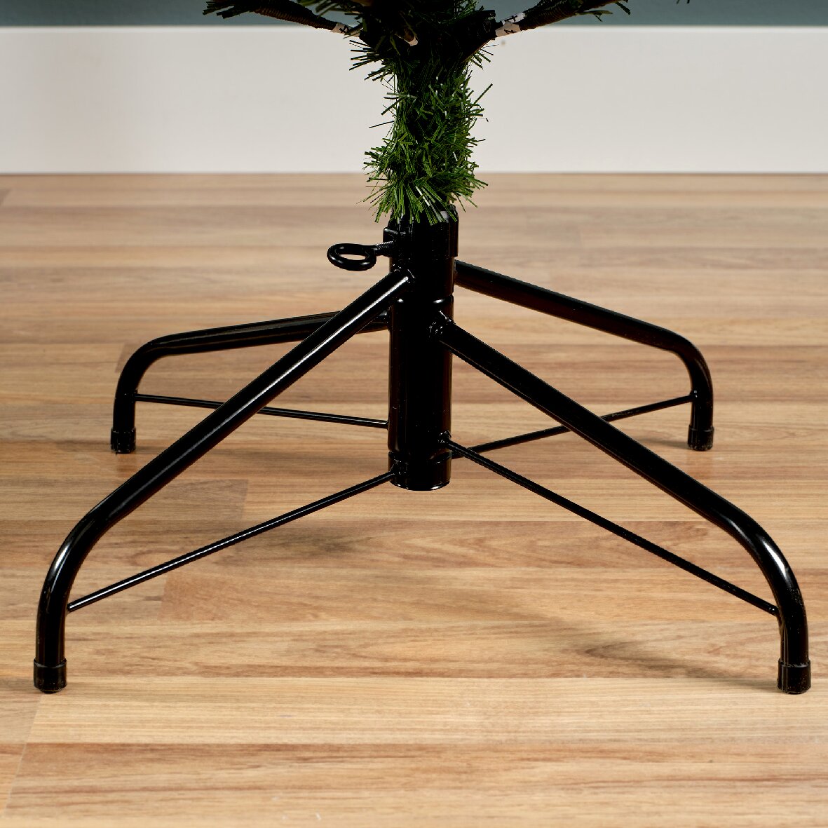 Nahaufnahme eines stabilen schwarzen Metallständers für einen künstlichen Weihnachtsbaum auf einem Holzboden.