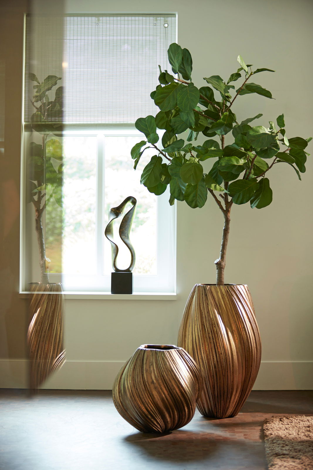 Zwei dekorative Vasen mit geschwungenem Design in einem modernen Raum, eine große Vase mit Pflanze und eine kleinere Vase, seitliche Perspektive.