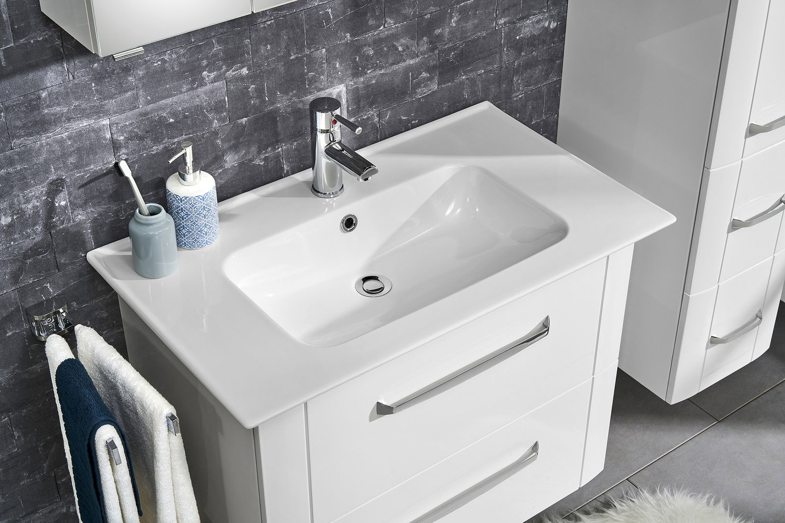 Moderner Keramikwaschtisch mit integriertem Wasserhahn und Stauraum, aus der Vogelperspektive fotografiert.