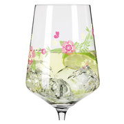 Nahaufnahme eines Weinglases mit floralen Mustern und Eiswürfeln, gefüllt mit einem Getränk und einer Limettenscheibe.