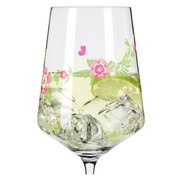 Close-up van een wijnglas met bloemmotieven en ijsblokjes, gevuld met een drankje en een schijfje limoen.
