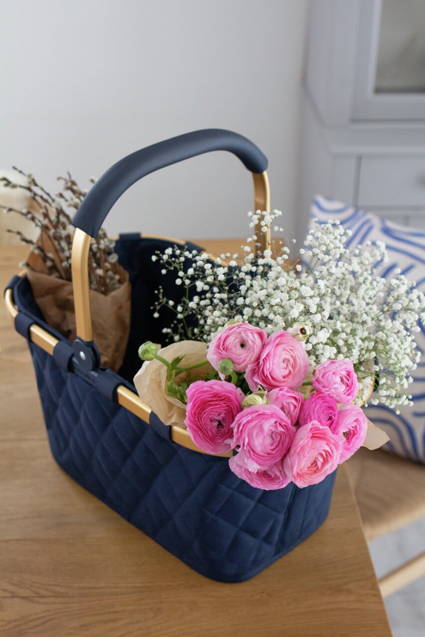 Draagtas met ruitpatroon in middernachtblauw, gevuld met bloemen, gefotografeerd vanaf een schuine hoek boven een tafel.