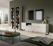 Modernes Wohnzimmer-Setup mit weißem TV-Lowboard auf schwarzen Metallfüßen, zwei hohen offenen Regalen und wandmontiertem Fernseher vor olivgrüner Wand, aufgenommen in schräger Frontansicht aus leicht erhöhter Perspektive.