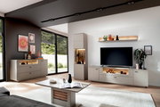 Modernes Wohnzimmer mit TV-Lowboard, Highboard und Sideboard in Hellgrau mit Holz-Akzenten und integrierter Beleuchtung, frontal aus leicht schräger Perspektive aufgenommen