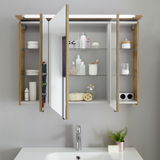 Badezimmerschrank mit Spiegel und Holzrahmen, geöffnet, mit verschiedenen Pflegeprodukten und Accessoires auf den Regalen, aus frontaler Perspektive.