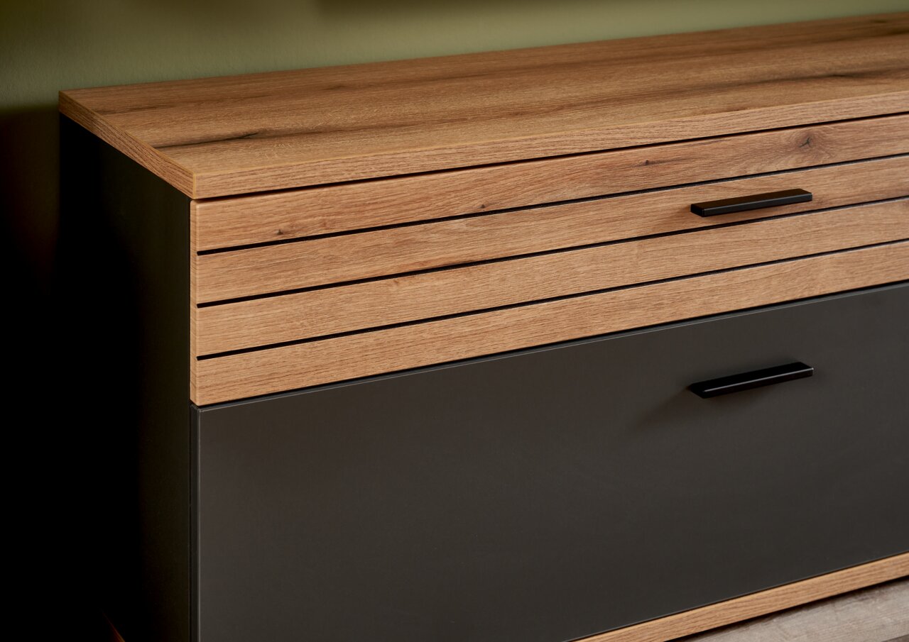 Nahaufnahme eines modernen TV-Lowboards mit Holz- und dunklen Elementen, seitliche Perspektive