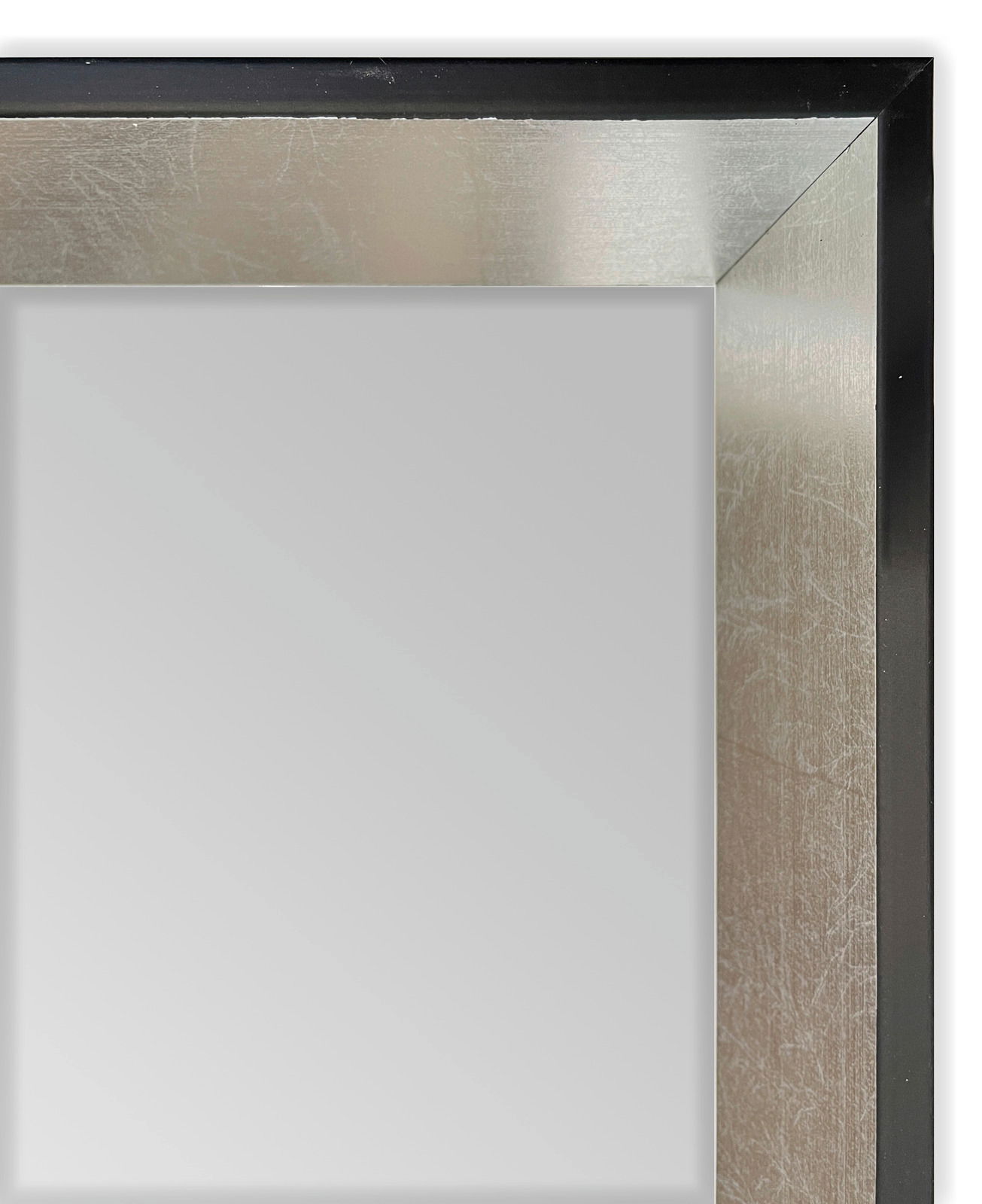 Nahaufnahme eines Wandspiegels mit einem eleganten, silbernen Rahmen und schwarzem Rand, perspektivisch von der Ecke aufgenommen.