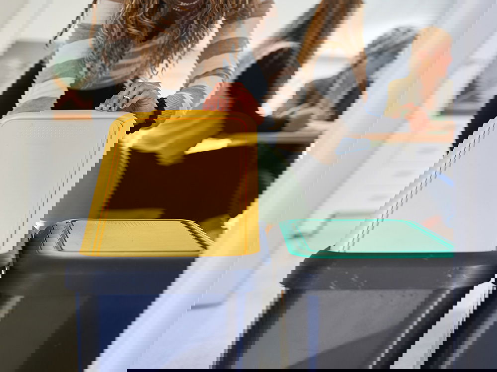 Mitarbeiterin trennt Abfall in Recyclingbehältern im Büro