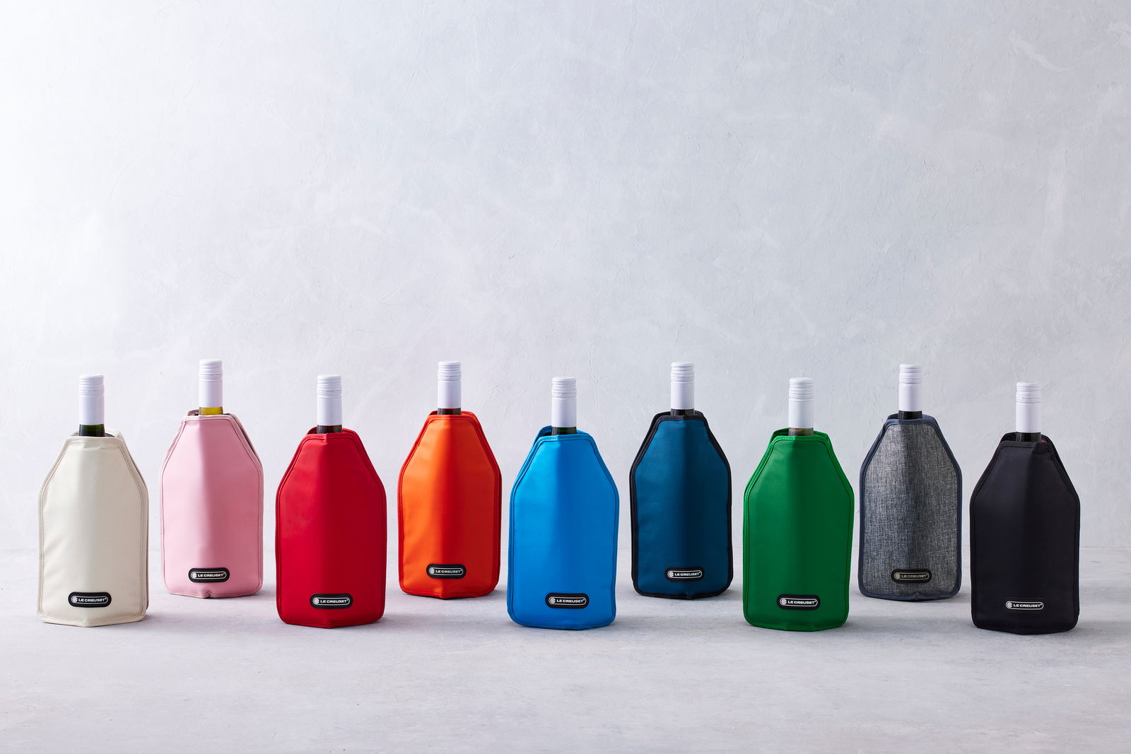 Verschiedene farbige Weinkühler in einer Reihe, frontal fotografiert, auf hellem Hintergrund.