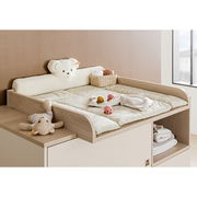 Wickelaufsatz aus Holz mit weicher Wickelauflage, Kuscheltieren und Körbchen, seitliche Perspektive