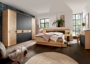 Modernes Schlafzimmer mit Holz- und Schwarzakzenten, bestehend aus einem großen Kleiderschrank, einem Bett mit integrierten Schubladen und zwei Nachttischen, aus der Perspektive von der Zimmerecke aus gesehen.