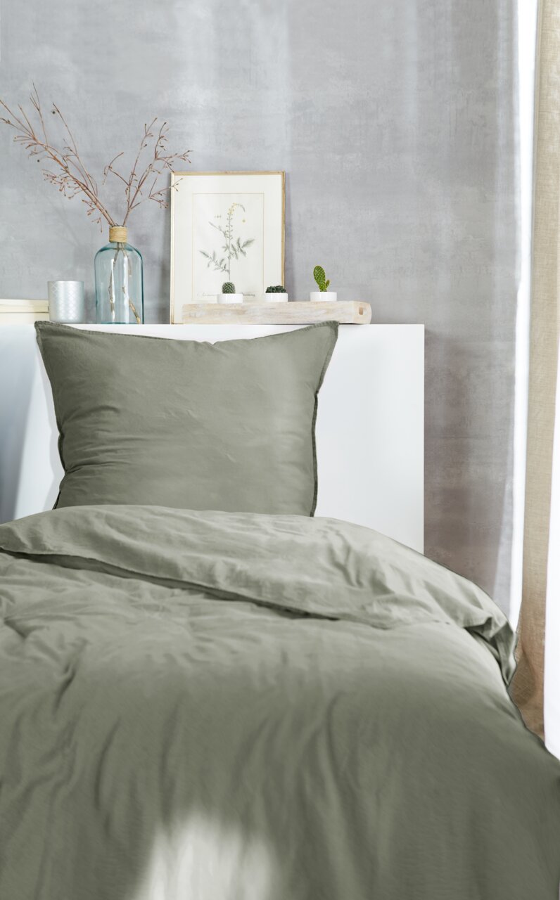 Westminister Bettwäsche STONE-WASHED Grüne Bettwäsche 135x200cm auf einem Bett, fotografiert aus der Vorderansicht, mit dekorativen Elementen im Hintergrund.