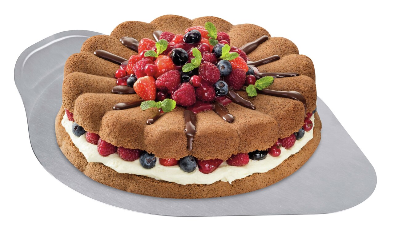 Tortenretter aus Edelstahl mit einer dekorativen Torte, die mit frischen Beeren und Schokoladensauce verziert ist, aus der Vogelperspektive.