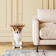 Beistelltisch mit Hundemotiv, der ein Tablett in Form einer Holzscheibe hält, neben einem Sofa in einem Wohnzimmer. Frontalansicht.