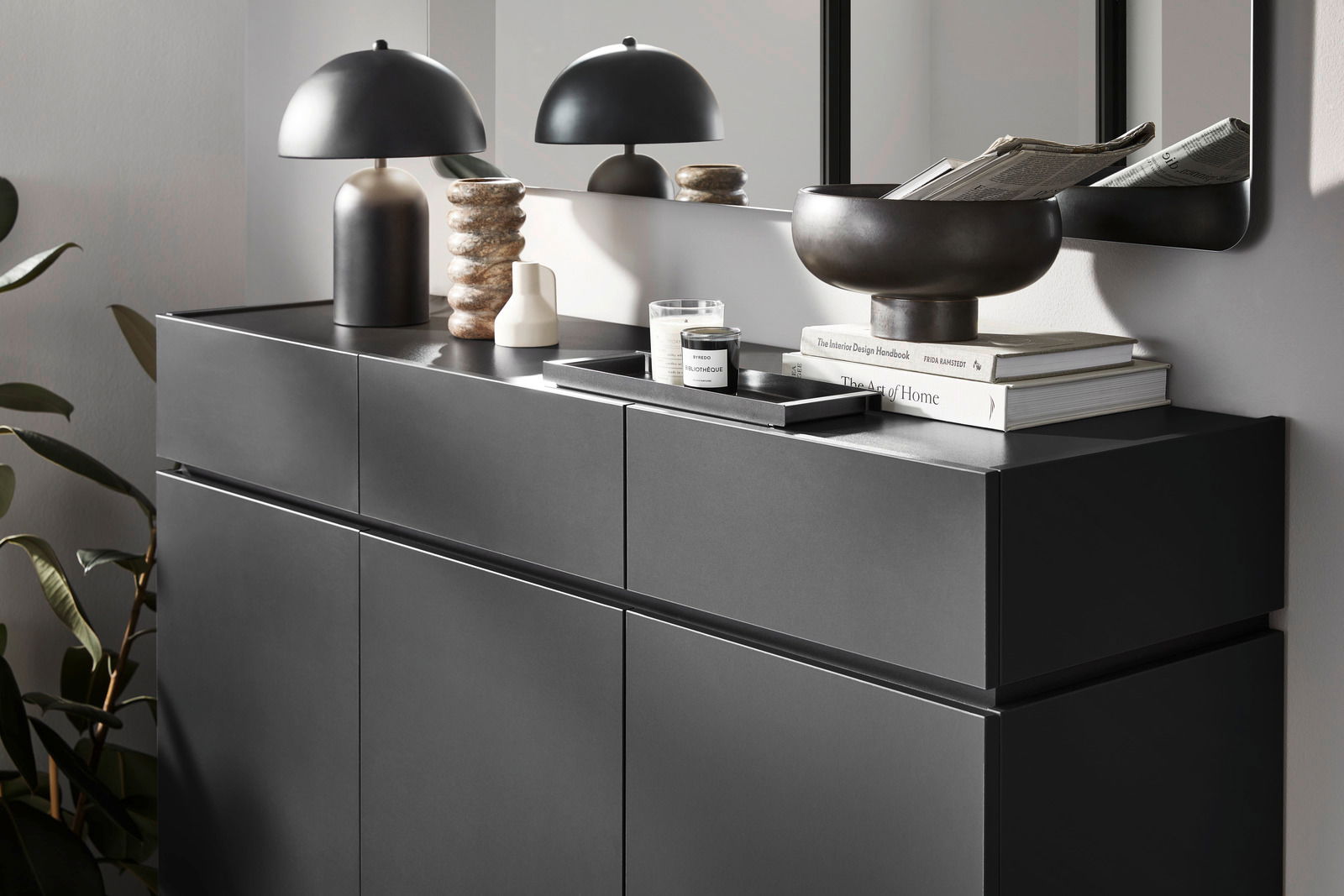 Moderner XL-Schuhschrank in dunklem Design, seitliche Perspektive, dekoriert mit Lampe, Büchern und Schale.