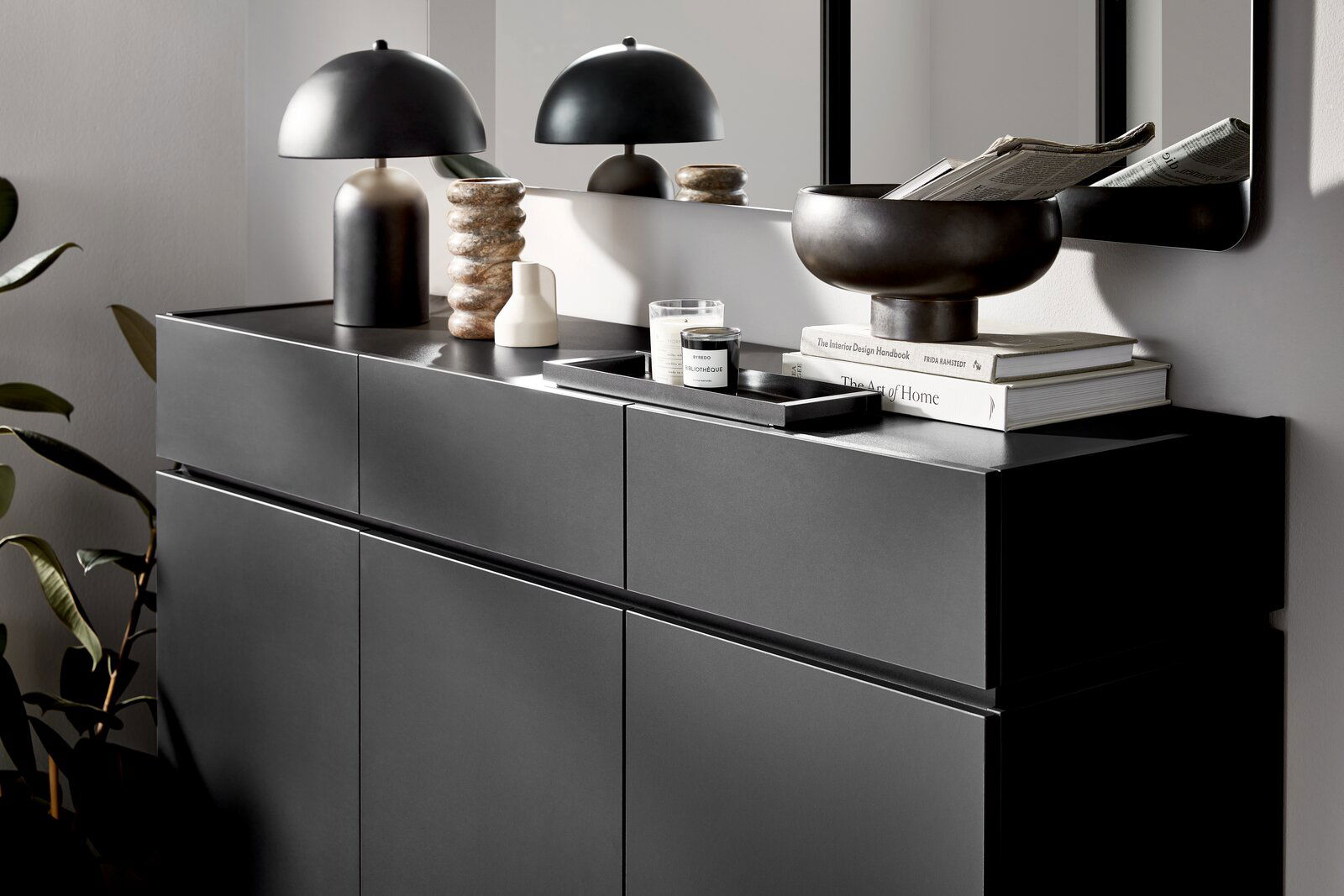 Moderner XL-Schuhschrank in dunklem Design, seitliche Perspektive, dekoriert mit Lampe, Büchern und Schale.