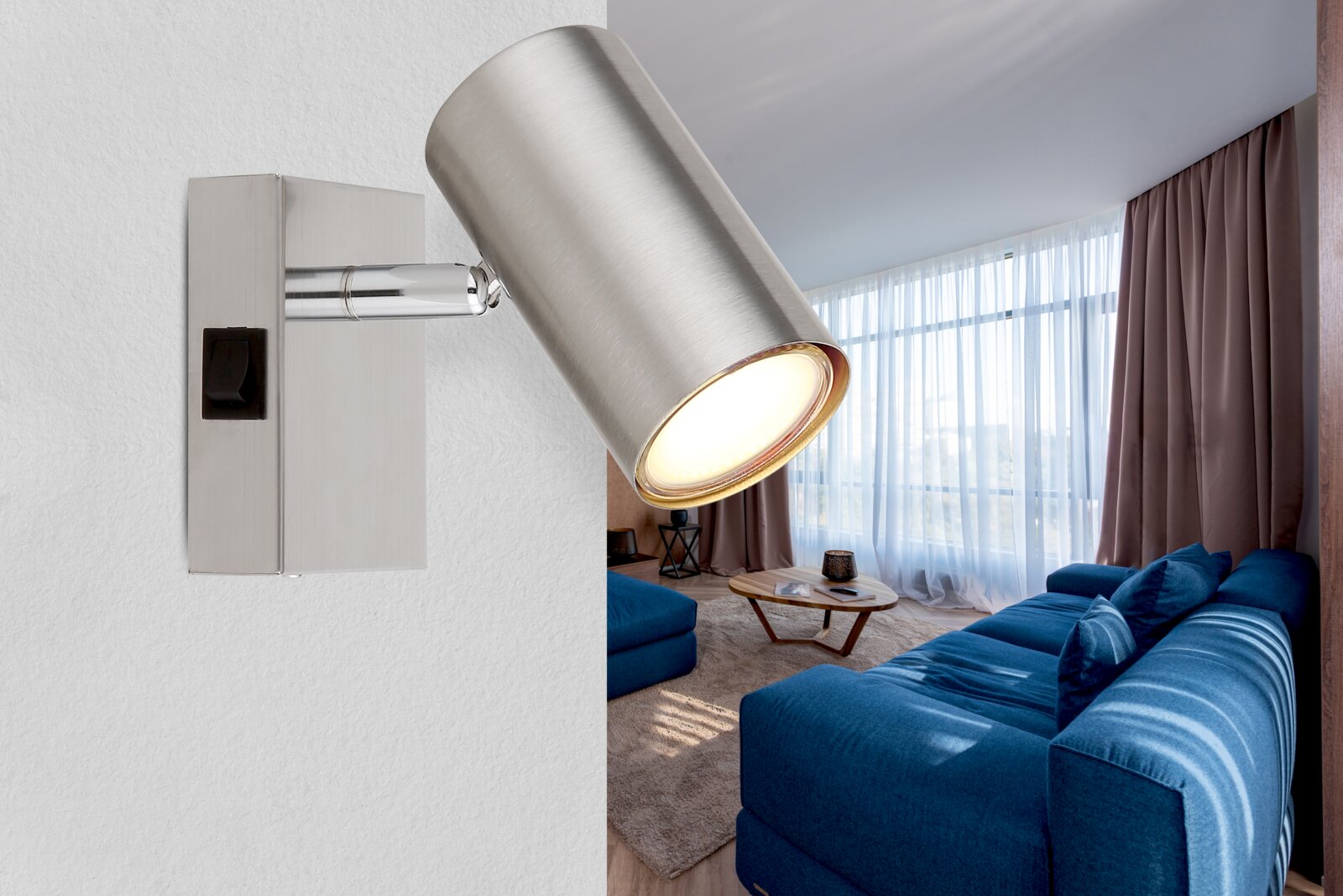 Moderner Wandstrahler aus gebürstetem Metall, seitliche Perspektive, montiert an einer Wand in einem stilvollen Wohnzimmer mit blauer Couch und großen Fenstern.