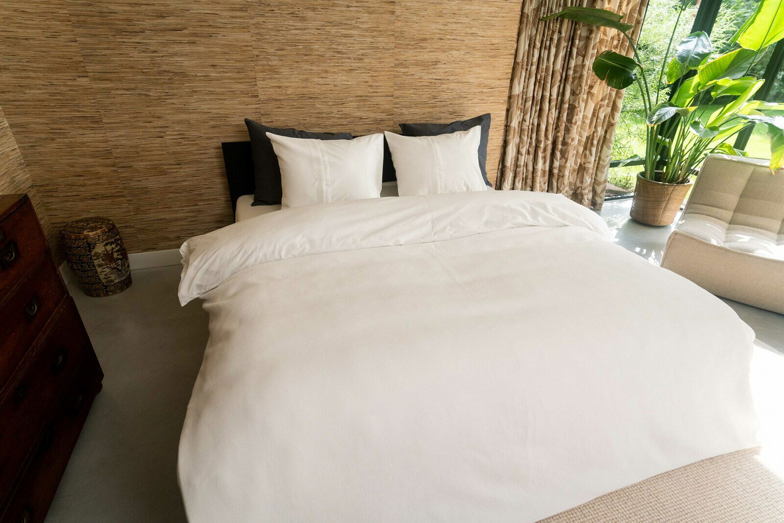 Bett mit weißer Bettwäsche in einem stilvoll eingerichteten Schlafzimmer, seitliche Perspektive