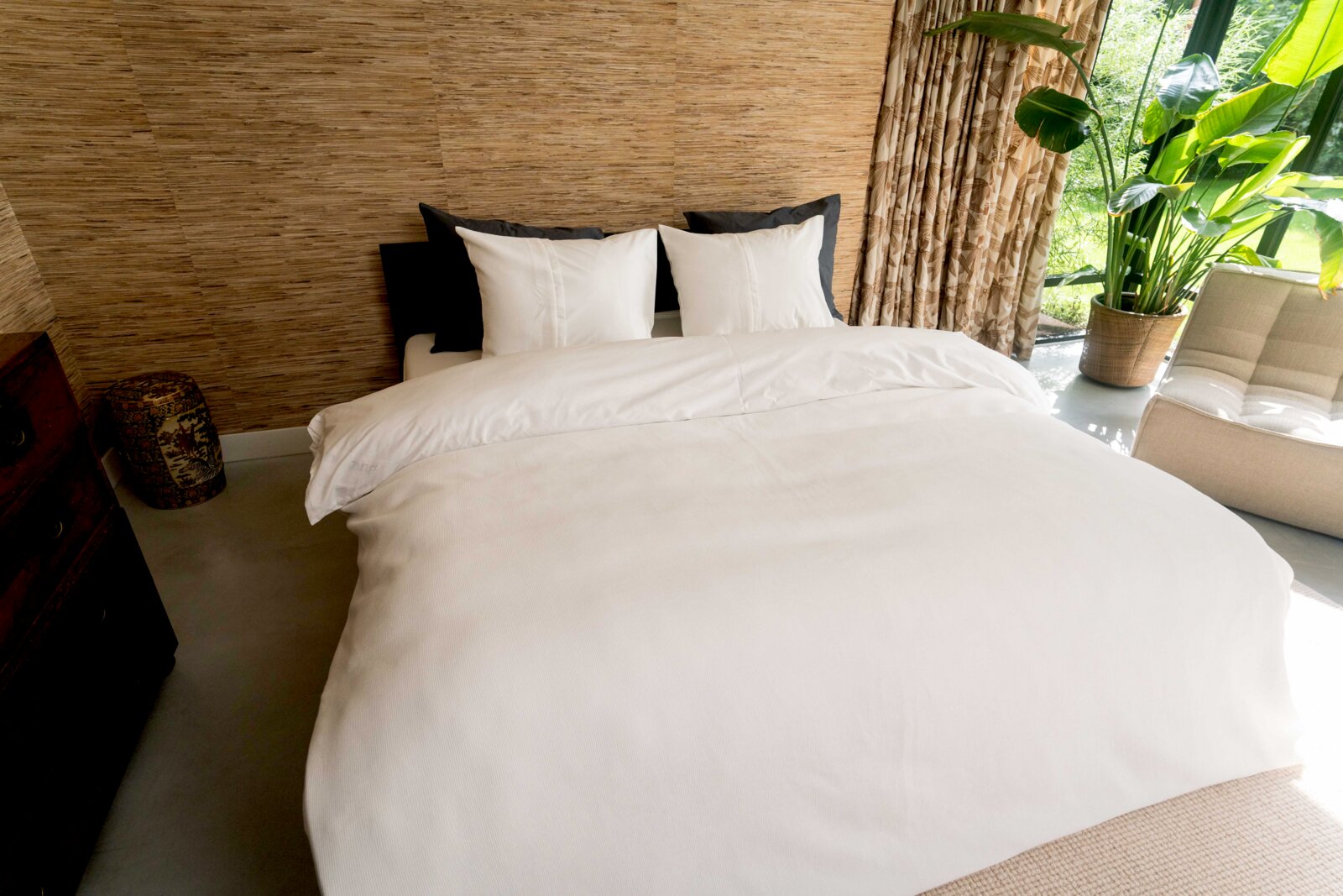 Bett mit weißer Bettwäsche in einem stilvoll eingerichteten Schlafzimmer, seitliche Perspektive