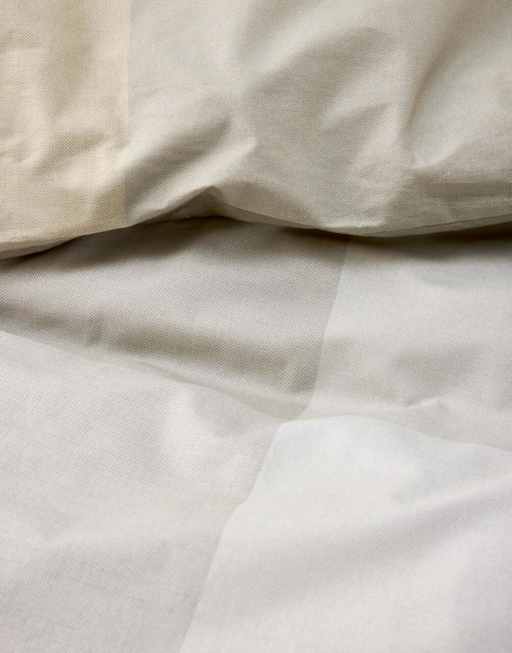 Nahaufnahme von beiger Bettwäsche mit leichtem Faltenwurf, Draufsicht
