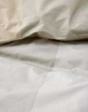 Close-up van beige beddengoed met lichte plooien, bovenaanzicht