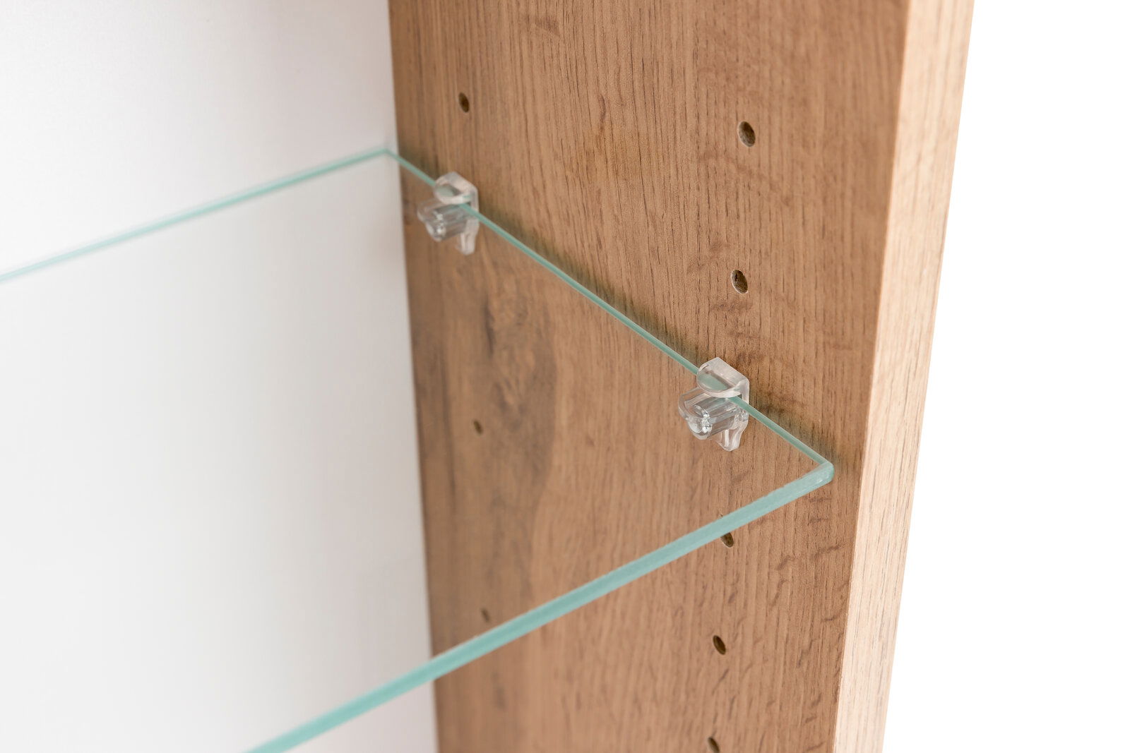 Nahaufnahme eines Spiegelschranks mit einem Glasregal, das an einer Holzwand befestigt ist. Perspektive von der Seite.