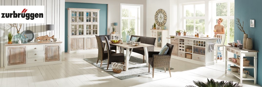 Ein helles Esszimmer mit Landhausstil-Möbeln, großem Tisch und schwarzen Rattanstühle.