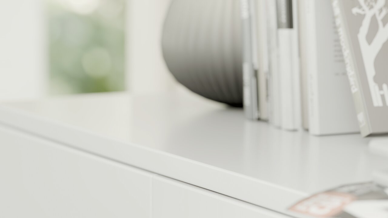 Nahaufnahme eines weißen Schuhschranks mit Büchern und einer Vase darauf, seitliche Perspektive.