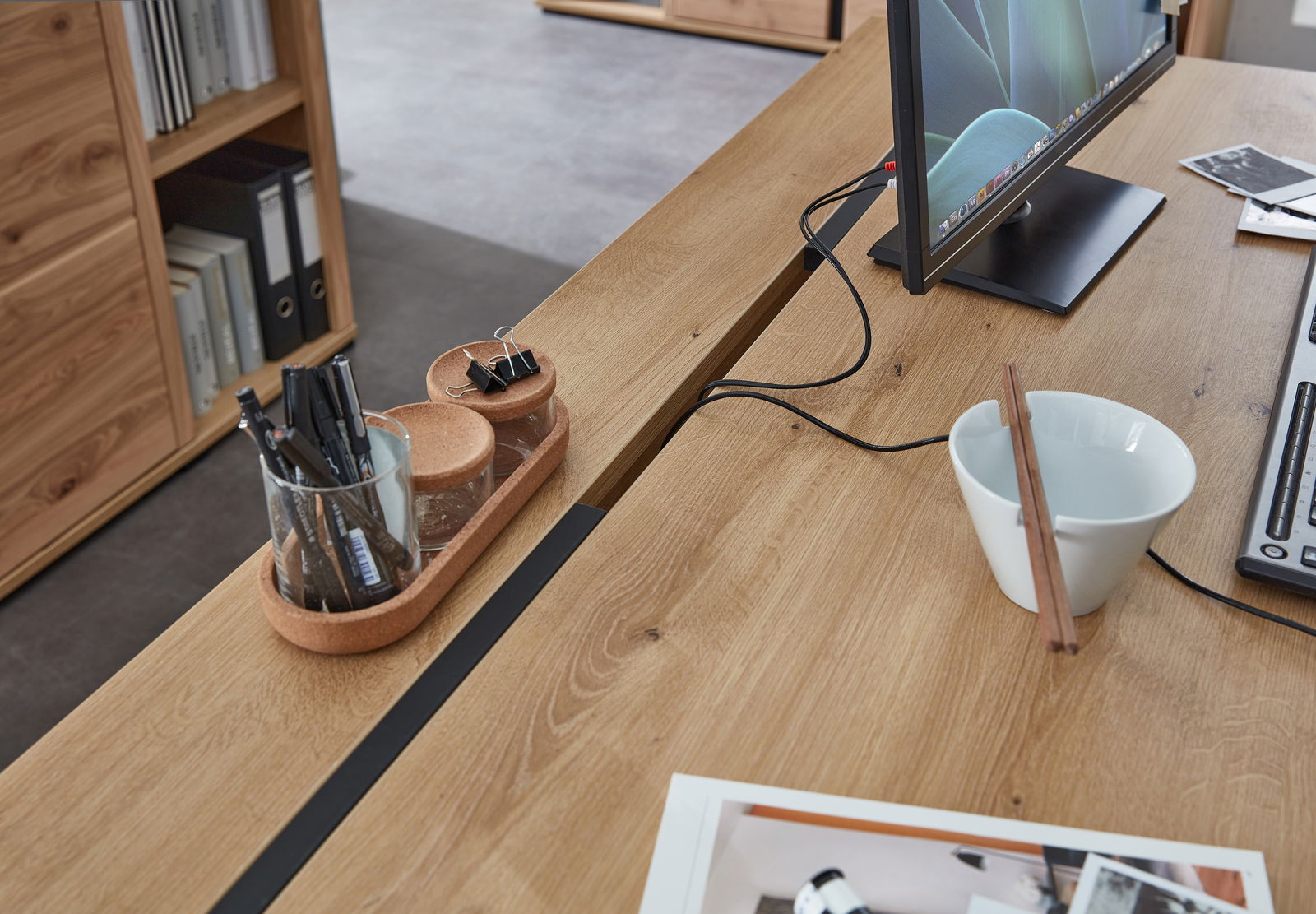 Moderner Schreibtisch aus Holz mit Monitor, Stiftehalter und Schale, seitliche Perspektive